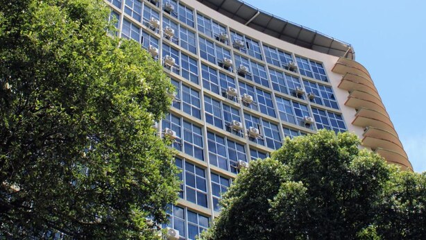 A modern building with a curved facade, large windows, and air conditioning units. - Real Minas Suites Hotel (Governador Valadares)