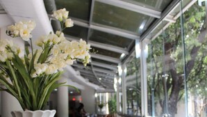 A restaurant with tables, chairs, and a large window with a view of trees. - Real Minas Suites Hotel (Governador Valadares)