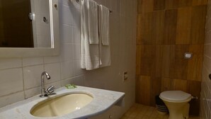 A bathroom with a sink, mirror, and toilet. - Real Minas Suites Hotel (Governador Valadares)