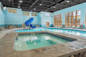 Ein Hallenbad mit blauer Rutsche, Liegestühlen und einem Rettungsschwimmerstand.