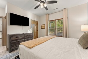 Ein Schlafzimmer mit einem Bett, einer Kommode, einem Fernseher, einem Deckenventilator und einem Fenster mit Jalousien.