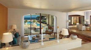 Una sala de estar moderna con vista a la piscina, una mesa de billar y un área de estar confortable.