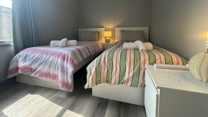 Ein Hotelzimmer mit zwei Betten, einem Nachttisch mit Lampe und einem Fenster mit Vorhängen.