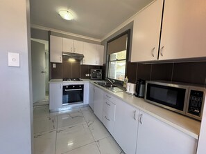 A kitchen with white cabinets, a built-in oven, a microwave, and a window. - Entire villa in Metford, 
A relaxing, homey stay — ideal for short breaks (Metford)