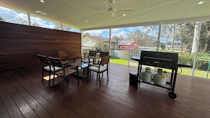 Eine Außenpatio mit Grill, Stühlen und Tisch.