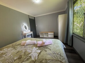 A bedroom with a bed, a vanity with a mirror, a bench, and a window with a view. - Entire villa in Metford, 
A relaxing, homey stay — ideal for short breaks (Metford)