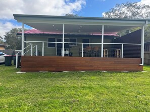 A covered outdoor area with a wooden bench, a car, and a fence in the background. - Entire villa in Metford, 
A relaxing, homey stay — ideal for short breaks (Metford)