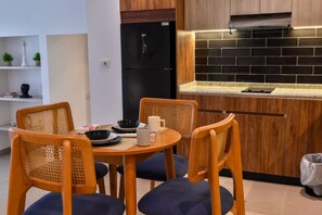 A compact kitchen with a black refrigerator, wooden cabinets, and a tiled backsplash. - Luxury stay at Degla by Spacey #67 (Cairo)