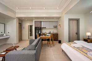 A modern hotel room with a sofa, a bed, a dining table with chairs, a kitchen area, and a bathroom. - Luxury stay at Degla by Spacey #67 (Cairo)