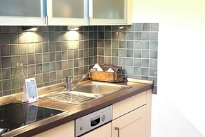 A modern kitchen with a stainless steel sink, a built-in oven, and a wooden countertop. - Your comfortable apartment, Alter Konsumverein, Apartment 1, in a central location on Sylt (Sylt)