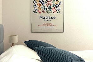 A framed artwork of Matisse's 'Et nyt liv' in a hotel room with a bed, pillows, and a lamp. - Your comfortable apartment, Alter Konsumverein, Apartment 1, in a central location on Sylt (Sylt)