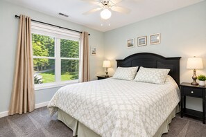 A bedroom with a large bed, two bedside tables with lamps, a ceiling fan, and a window with curtains. - 🌊 Beechnut Cove | Lake Gaston Escape • Private Dock • Game Room • Fire Pit 🔥 (Littleton)