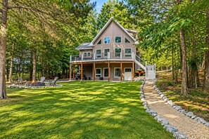 A two-story house with a deck, surrounded by a well-maintained lawn and trees. - 🌊 Beechnut Cove | Lake Gaston Escape • Private Dock • Game Room • Fire Pit 🔥 (Littleton)