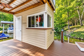A wooden deck with a small cabin-style building, a dock with boats, and a pond. - 🌊 Beechnut Cove | Lake Gaston Escape • Private Dock • Game Room • Fire Pit 🔥 (Littleton)