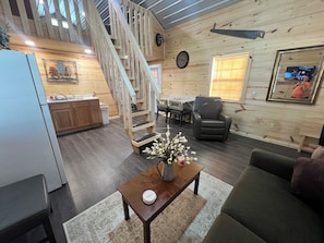 A wooden interior with a staircase, a dining area, a sofa, and a coffee table.