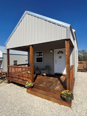 A single-story building with a porch, a door, and a window.