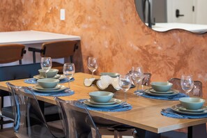 A dining table set with multiple bowls and wine glasses, with chairs around it. - Leave the car parked. Edmonton's best cafés & restaurants are minutes' walk away, downtown 5 by car. Your brand-new upper home: gallery walls, chef-style kitchen with a gas range, fireplace, A/C & patio. For professionals & families, room for 9. (Edmonton)
