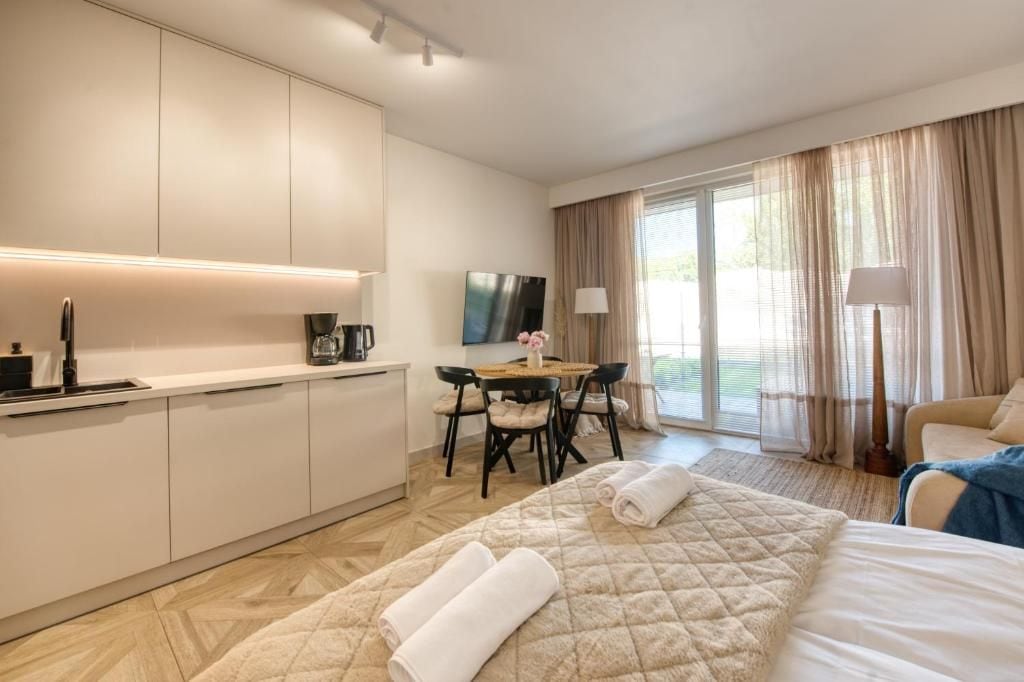 Een hotelkamer met een bed, bureau, stoel, televisie en een raam met gordijnen.