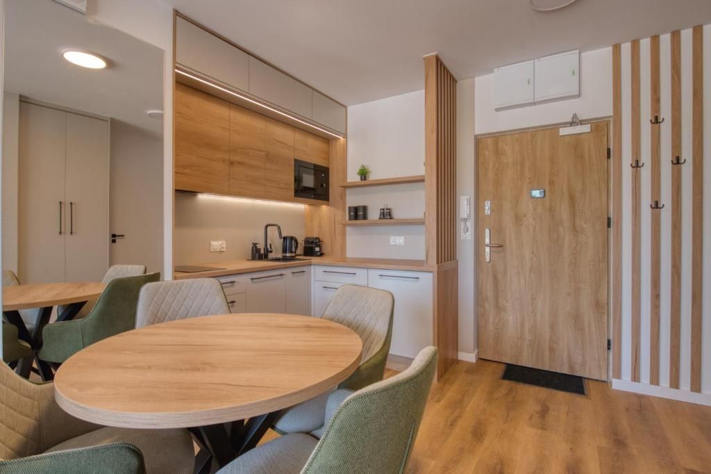 A modern kitchen with wooden cabinets, a microwave, and a round dining table with chairs.