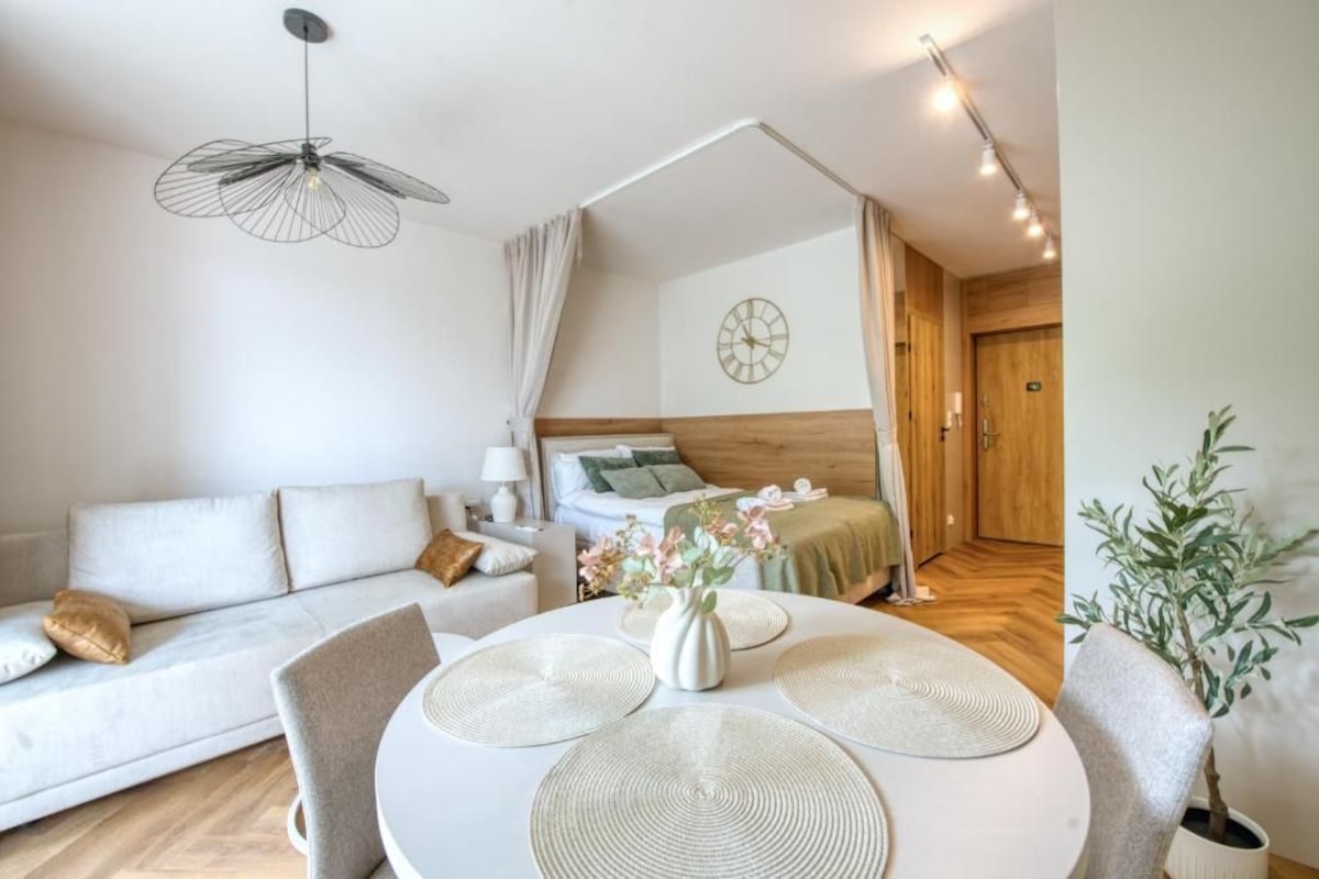 Een moderne, goed verlichte slaapkamer met een houten hoofdbord, een nachtkastje met een lamp, en uitzicht op een gang.