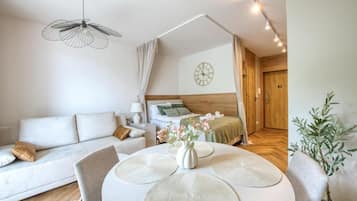 A modern, well-lit bedroom with a wooden headboard, a bedside table with a lamp, and a view into a hallway.