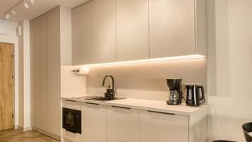 Una cocina moderna con horno empotrado, fregadero y cafetera.