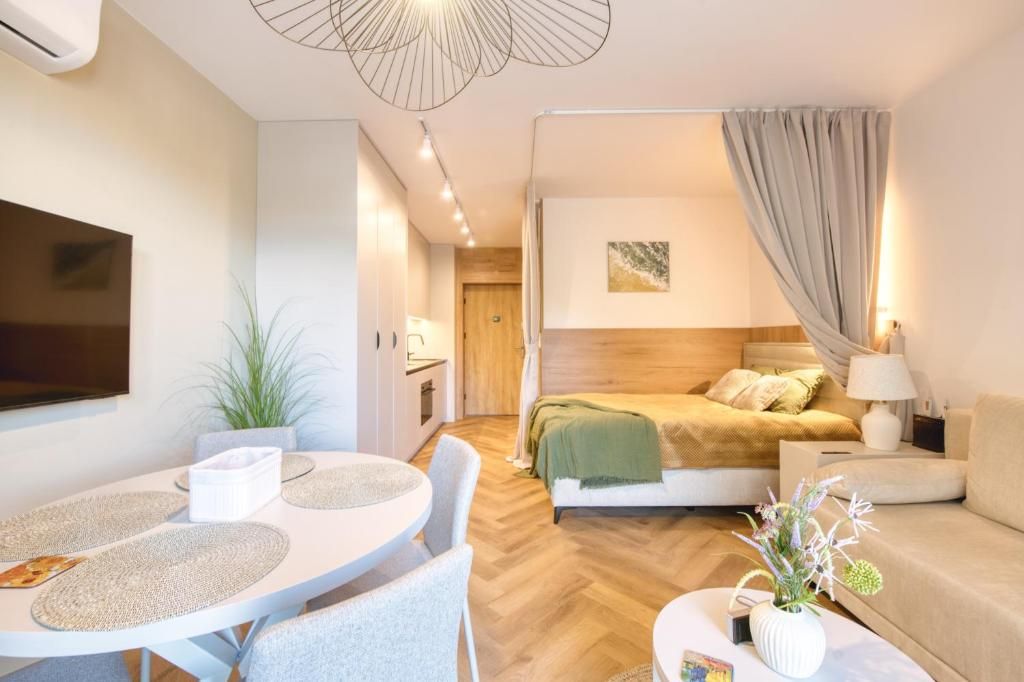 Quarto moderno com cama, mesa de cabeceira e televisão na parede.