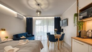 Moderni hotellihuone, jossa on sänky, ruokailutila ja pieni keittiö.