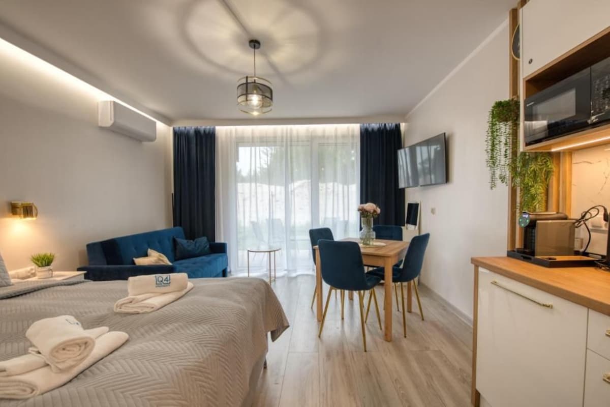 Een moderne hotelkamer met een bed, een eethoek en een kitchenette.