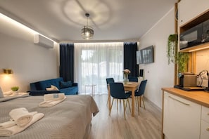 Een moderne hotelkamer met een bed, een eethoek en een kitchenette.