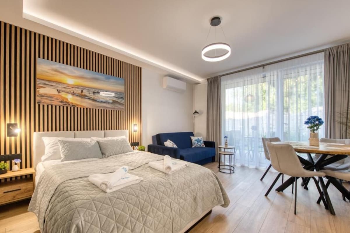 Een moderne hotelkamer met een groot bed, een bank, een eettafel en een schilderij aan de muur.