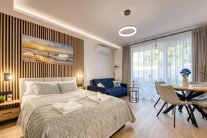Una habitación de hotel moderna con una cama grande, un sofá, una mesa de comedor y un cuadro en la pared.