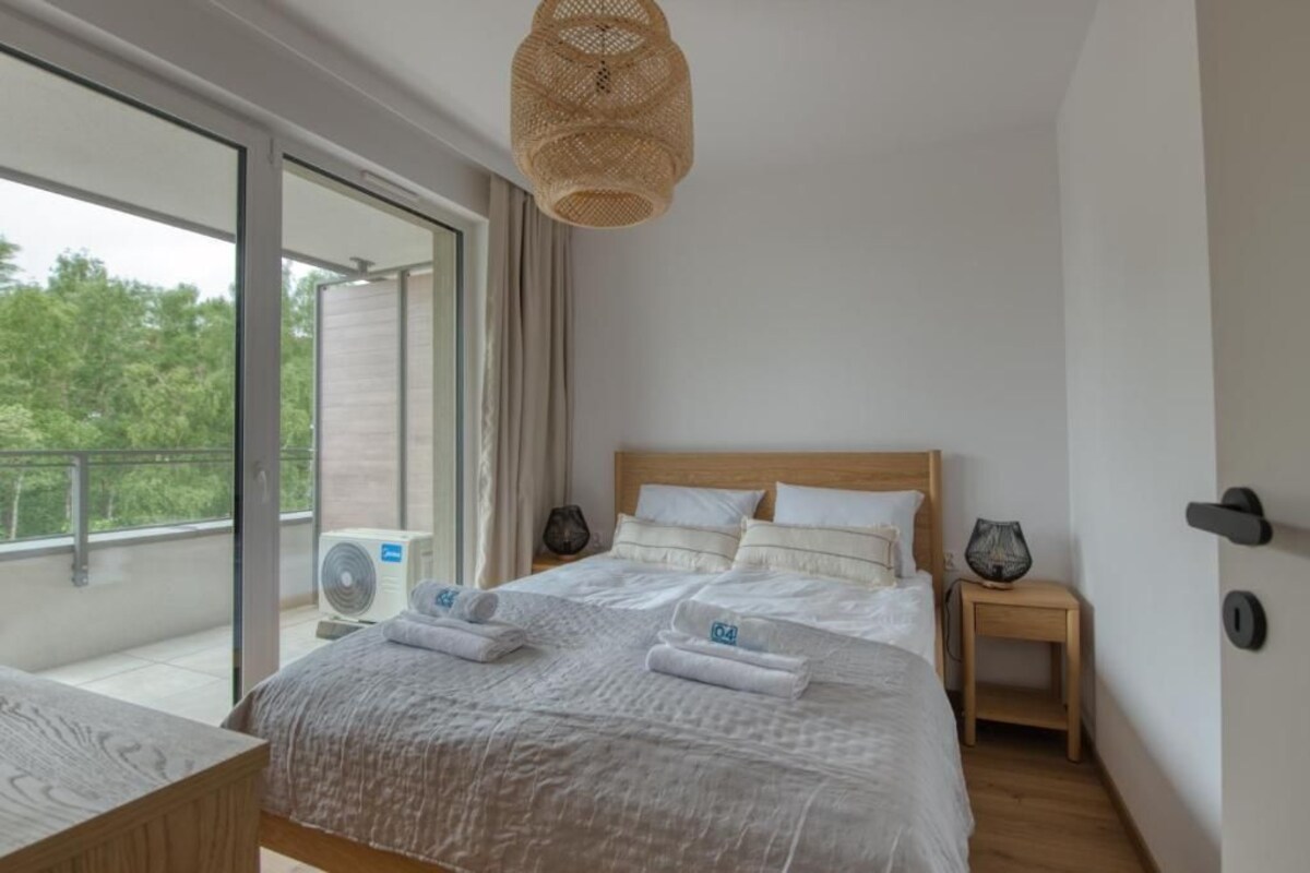 Een hotelkamer met een groot bed, een nachtkastje, een klein tafeltje, een plafondventilator en uitzicht door een schuifdeur.