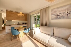 Un espacio habitable moderno con sofá, mesa de comedor, sillas y una zona de cocina.