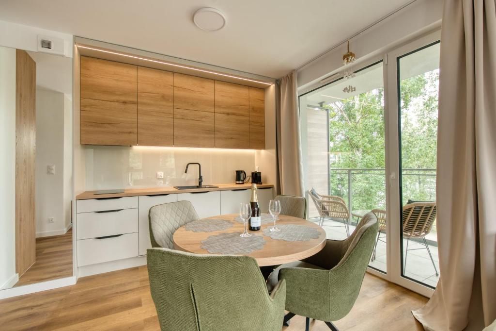 Una cocina moderna con armarios de madera, una mesa de comedor con sillas y un balcón con mobiliario para exterior.