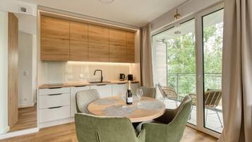 Una cocina moderna con armarios de madera, una mesa de comedor con sillas y un balcón con mobiliario para exterior.