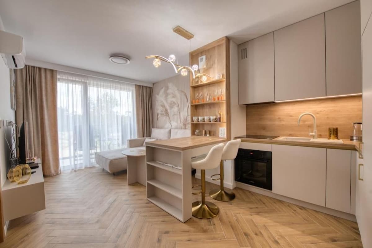 A modern kitchen with a central island, bar stools, and a built-in oven.
