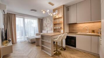 A modern kitchen with a central island, bar stools, and a built-in oven.