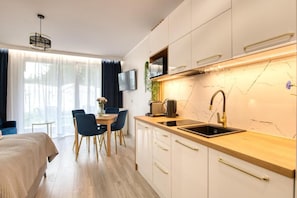 A modern kitchen with a wooden countertop, a built-in sink, and a stainless steel faucet. - Apartamenty Wydmove by Q4 Apartments  (Łeba)