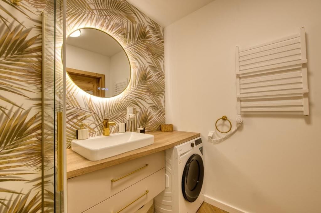 A bathroom with a sink, mirror, and washing machine.