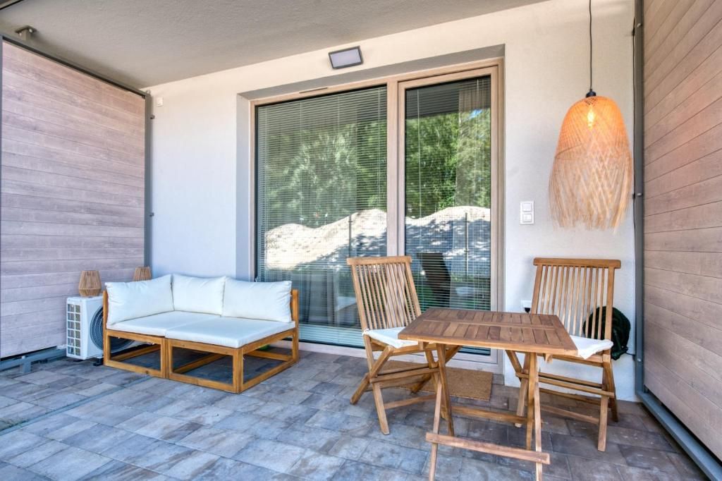 Eine überdachte Terrasse mit einem Holztisch und -stühlen, einer Couch und einer hängenden Lampe.