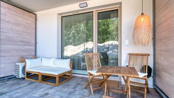 Eine überdachte Terrasse mit einem Holztisch und -stühlen, einer Couch und einer hängenden Lampe.