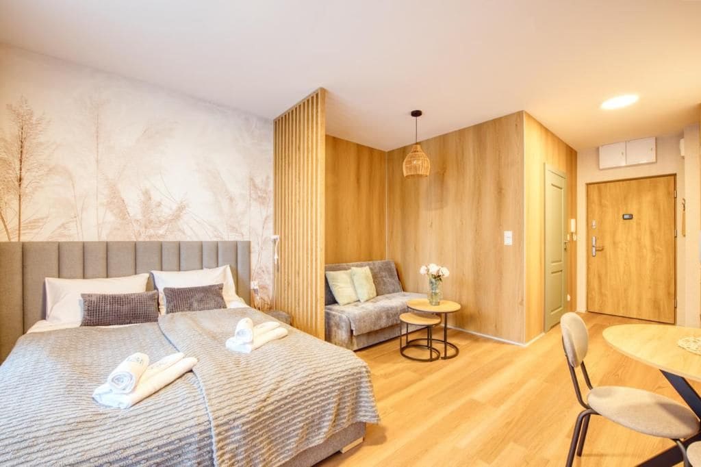 Quarto de hotel com uma cama grande, um sofá, uma mesinha redonda e uma cadeira.