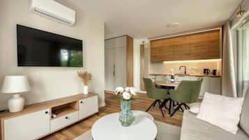 A modern living room with a flat-screen TV, a coffee table with a vase of flowers, and a sofa.