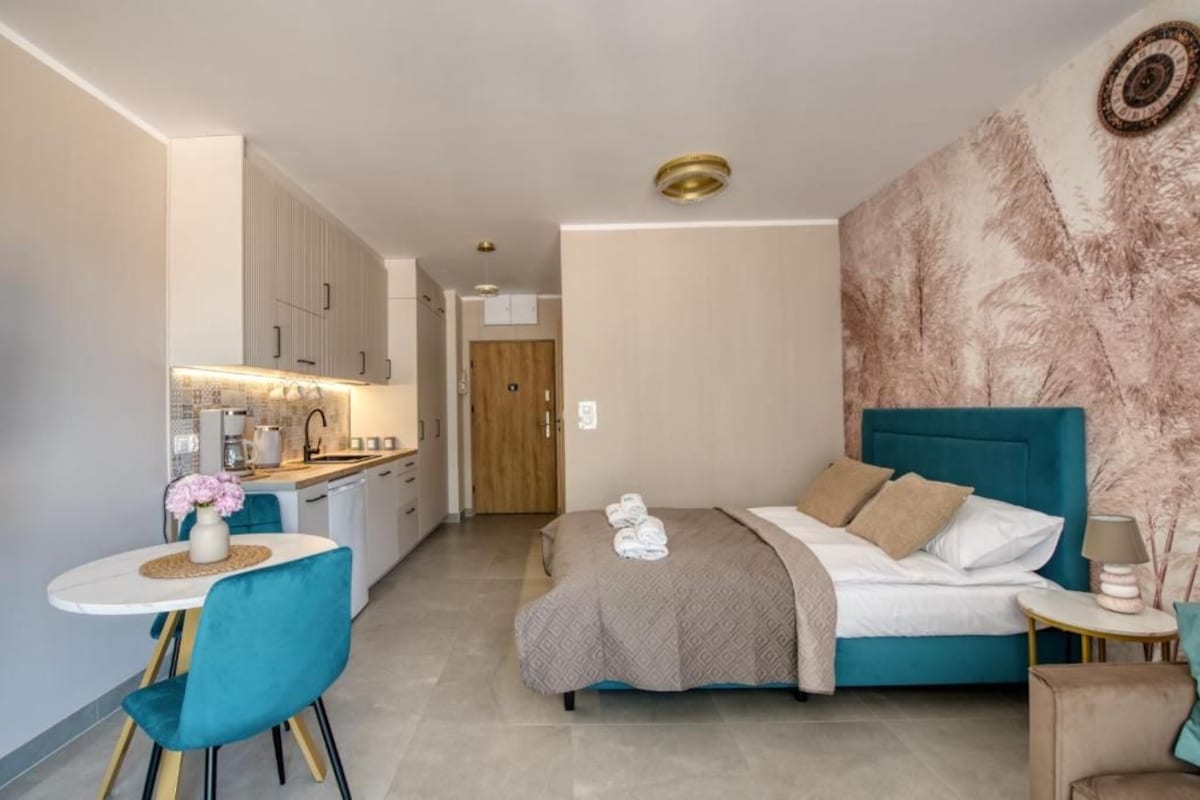Een knus hotelkamer met een bed, nachtkastje en een kleine zithoek met een tafel en stoelen.