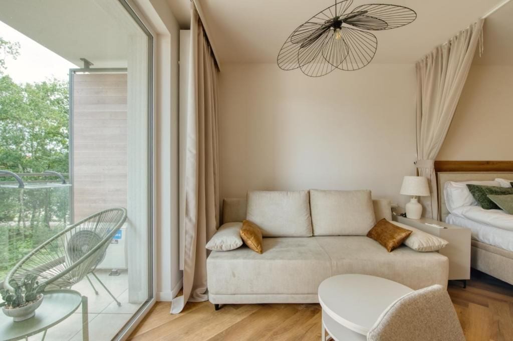 Un dormitorio moderno con sofá, mesita de noche, lámpara y una lámpara colgante.