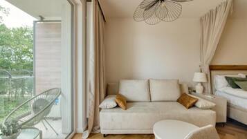 Un dormitorio moderno con sofá, mesita de noche, lámpara y una lámpara colgante.