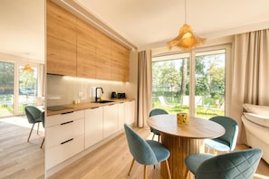 Een moderne keuken met houten kastjes, een ronde eettafel en blauwe stoelen.
