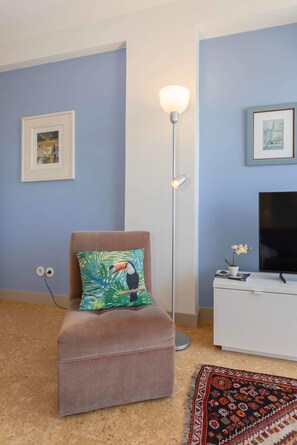 A living room with a brown sofa, a floor lamp, a television, and a framed picture on the wall. - Liiiving in Porto - Lobo Studio II (Porto)