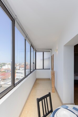 A balcony with a view of buildings, a chair, and a table with plates. - Liiiving in Porto - Lobo Studio II (Porto)